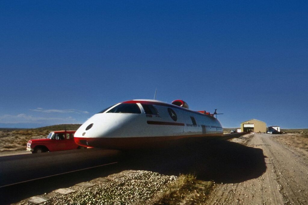 a white and red train traveling down a dirt road