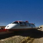 a white and red train traveling down a dirt road